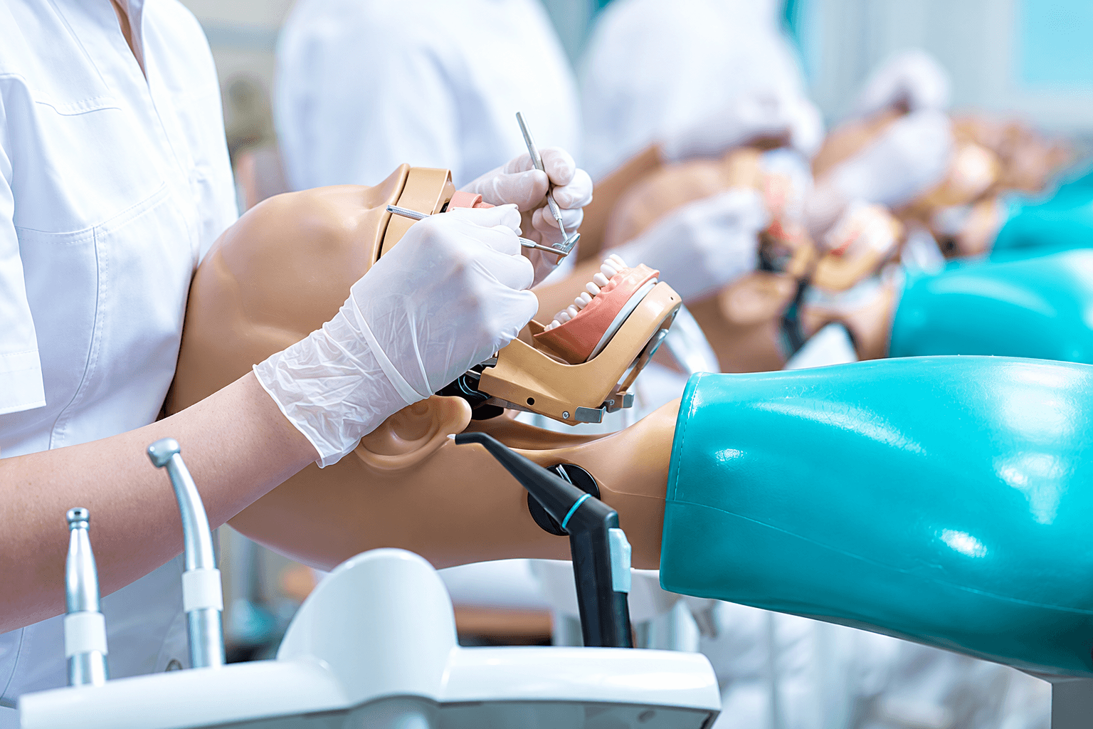 A dental student practicing with a dental training mannequin.